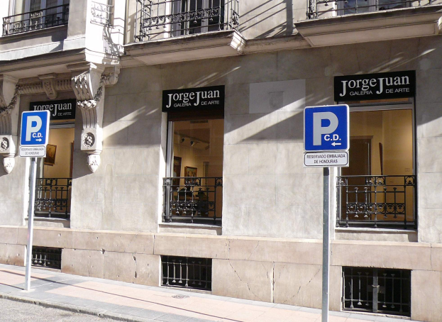 Ein mehrstöckiges Gebäude mit Fenstern, Geländern, Türen und Säulen, das Schilder an Pfosten am Gehweg und sichtbare Innenobjekte zeigt, die auf eine belebte städtische Umgebung hinweisen.