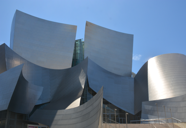Das ARTIST Concert Hall in Los Angeles, ein modernes Gebäude mit Glaswänden und Treppen mit Geländern, die zum Eingang führen, umgeben von Laternenmasten, mit einer Tafel mit Text im Vordergrund und einem bewölkten Himmel im Hintergrund.