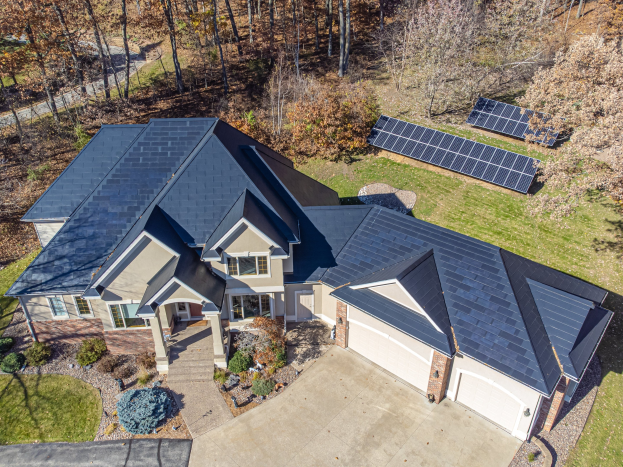 Luftaufnahme eines Hauses in North Carolina mit Solarpanelen auf dem Dach, umgeben von grünem Gras, Pflanzen und B├Ąumen.