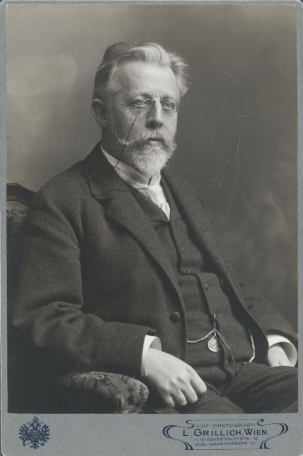 Schwarz-weiß-Porträt eines bärtigen Mannes in Brille, sitzend in einem Stuhl, mit Text unten, der ihn als "L. Grillich Wien, den Gründer der deutschen Revolution" identifiziert