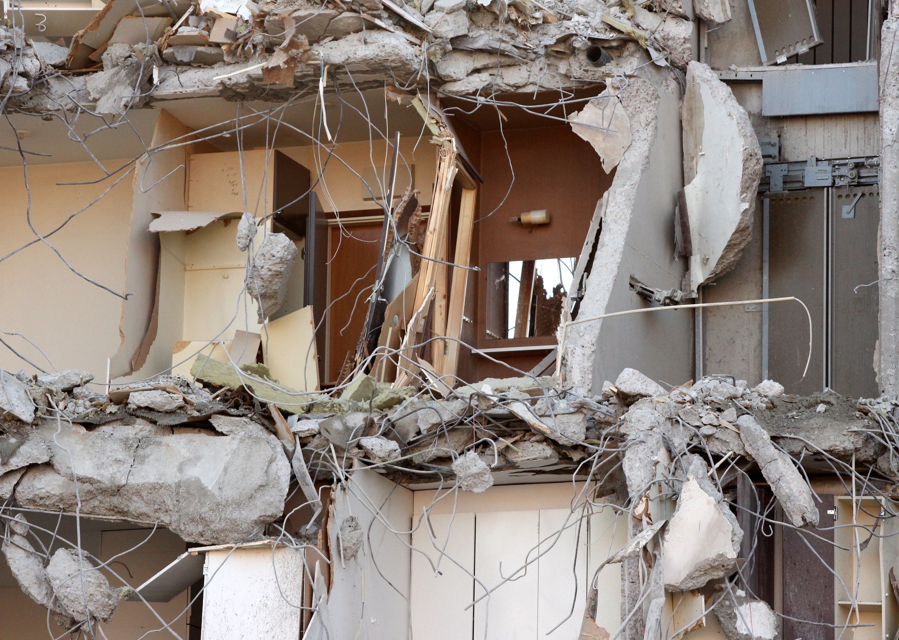 Teilweise abgerissenes Gebäude mit gebrochenen Wänden, verstreuter Trümmern und verstreuten Stücken von Holz und anderen Materialien auf dem Boden.