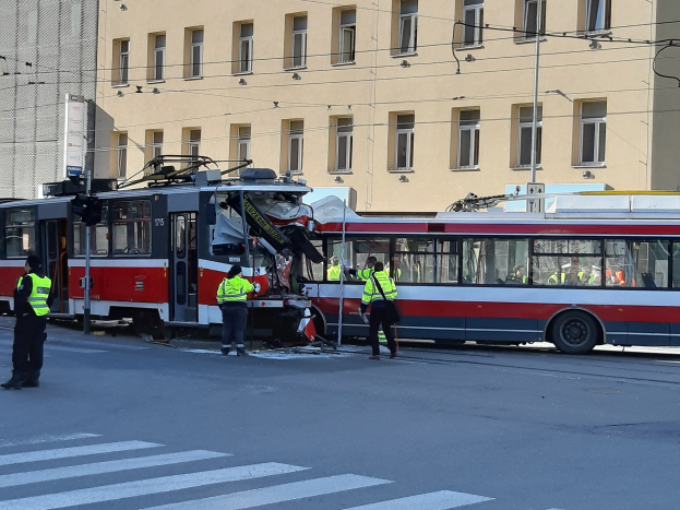 Rote und weiße Straßenbahn krachte auf die Seite der Straße mit ein paar Leuten in der Nähe und einem Gebäude im Hintergrund.