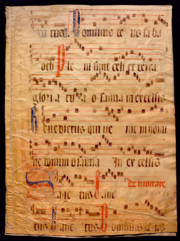 Ein illuminiertes Manuskript mit Notenschrift auf einem Blatt Papier vor dunklem Hintergrund, gefüllt mit Text und Musiksymbolen, die ein komplexes Design bilden.