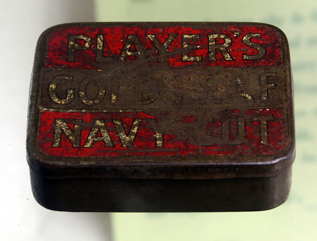 Kleines schwarzes und rotes Blechdöschen mit der Aufschrift "Player's Navy Cut" auf einem weißen Hintergrund mit unscharfem Hintergrund.