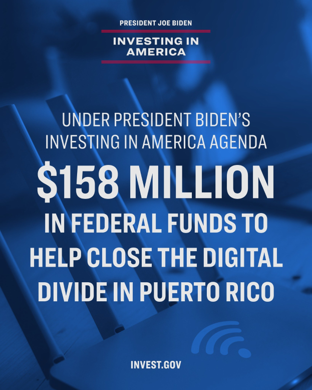 Plakat mit der Aufschrift "Unter Präsident Bidens America Investing Agenda: 158 Millionen Dollar Bundesmittel, um die digitale Kluft in Puerto Rico zu schließen" mit einem Laptop, Papieren und einem Kaffeebecher auf dem Tisch davor.