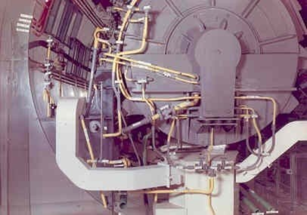 Großes industrielles Beschleunigergerät mit mehreren angeschlossenen Komponenten und Verkabelung innerhalb eines Gebäudes.