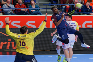 Eine Gruppe von Männern, die auf einem Platz Handball spielen, mit einem Ball in der Luft, in einer Arena mit Zuschauern und einem Schild mit der Aufschrift "Futsal-Weltmeisterschaft 2019 - Paris Saint-Germain vs Bordeaux".