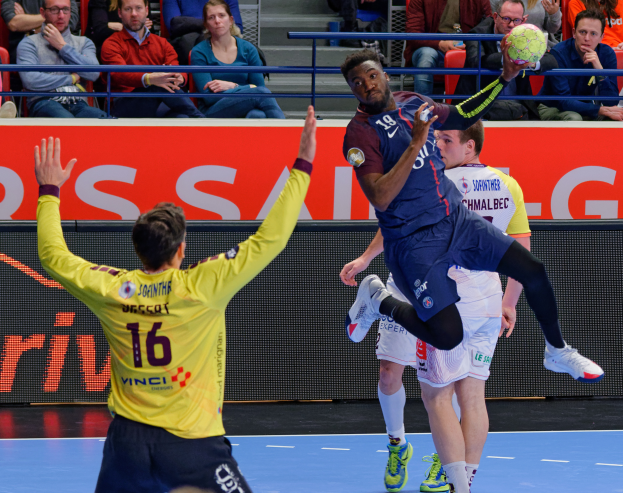 Eine Gruppe von Männern, die auf einem Platz Handball spielen, mit einem Ball in der Luft, in einer Arena mit Zuschauern und einem Schild mit der Aufschrift "Futsal-Weltmeisterschaft 2019 - Paris Saint-Germain vs Bordeaux".