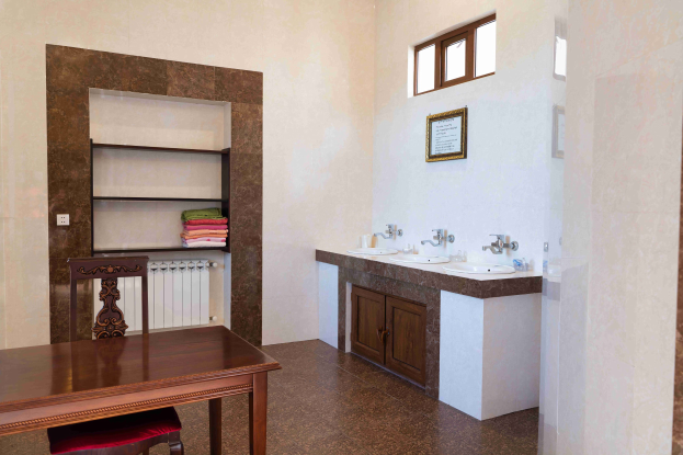 Bad mit zwei Waschbecken, Schränken, einem Tisch und Stühlen, einem Foto auf der Wand, einem Fenster und einem Handtuchhalter.