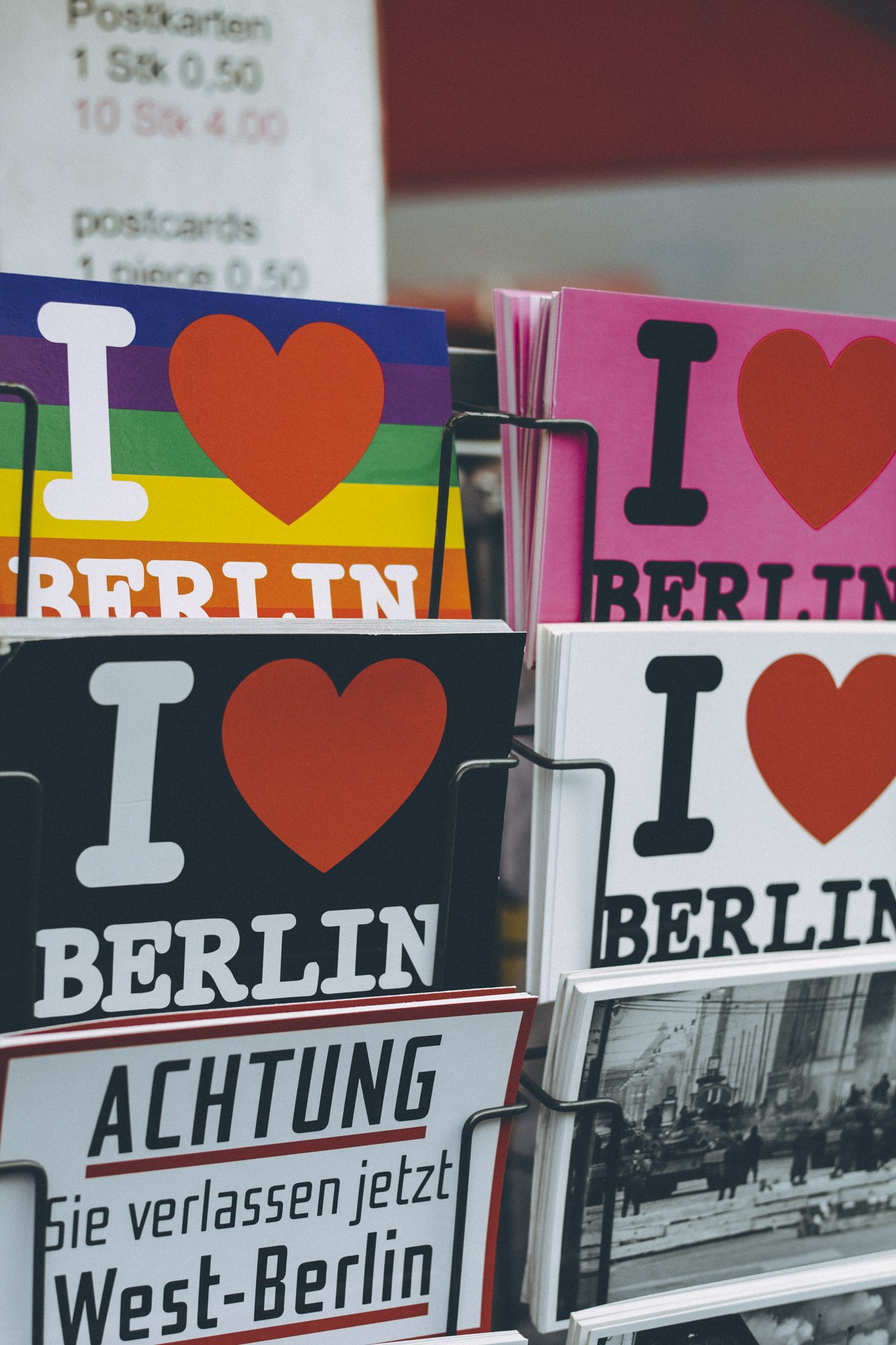 Ein Gestell mit Büchern und Postern, auf denen der Satz "Ich liebe Berlin" steht, vor einem leicht unscharfen, verträumten Hintergrund.
