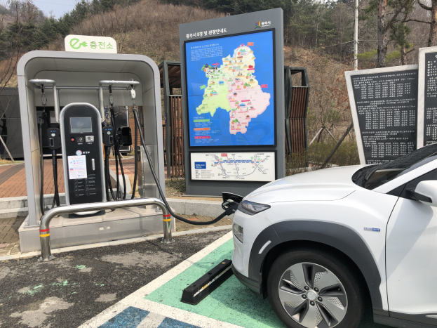 Laden eines Elektroautos an einer Station umgeben von Bäumen in Seoul, Südkorea.