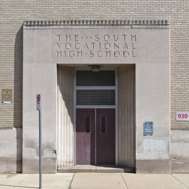 Das Südliche Berufsbildungszentrum mit einer Tür, Schildern und einem Wegweiser zum Eingang.