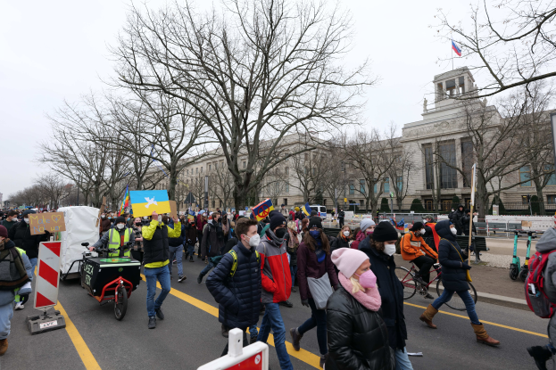 Eine große Gruppe von Menschen marschiert auf der Straße in Washington, D.C. am 21. Januar 2020, einige halten Schilder und Banner, andere fahren Fahrräder, mit Schildern, Bäumen und einem klaren blauen Himmel im Hintergrund.