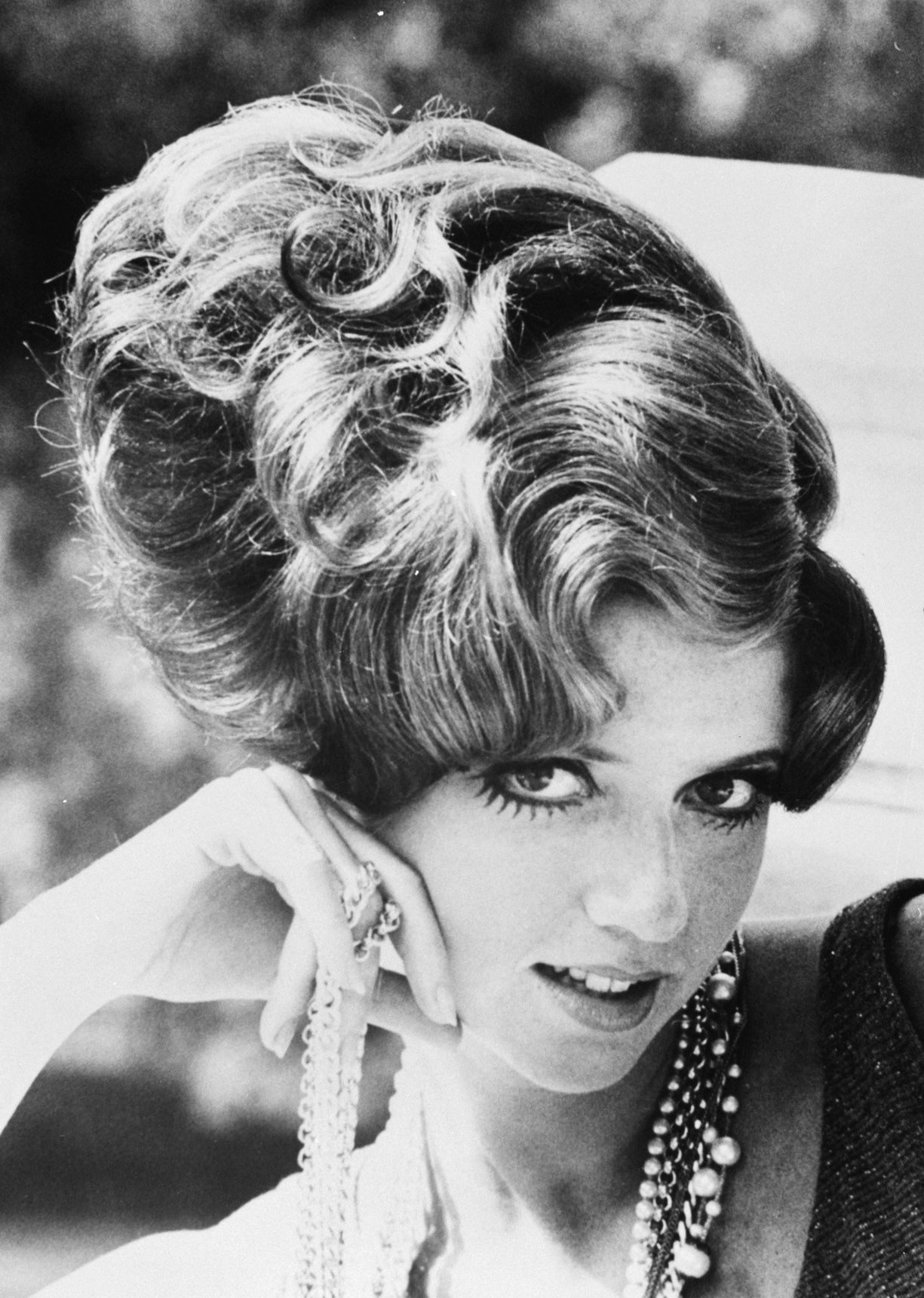 Schwarzes und weißes Foto von Prinzessin Diana in einem Kleid mit verzierten Accessoires, Hintergrund unscharf.