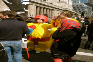 Ein Clown steht in der Mitte des Bildes, mit Menschen auf der linken und rechten Seite und Gebäuden oben.
