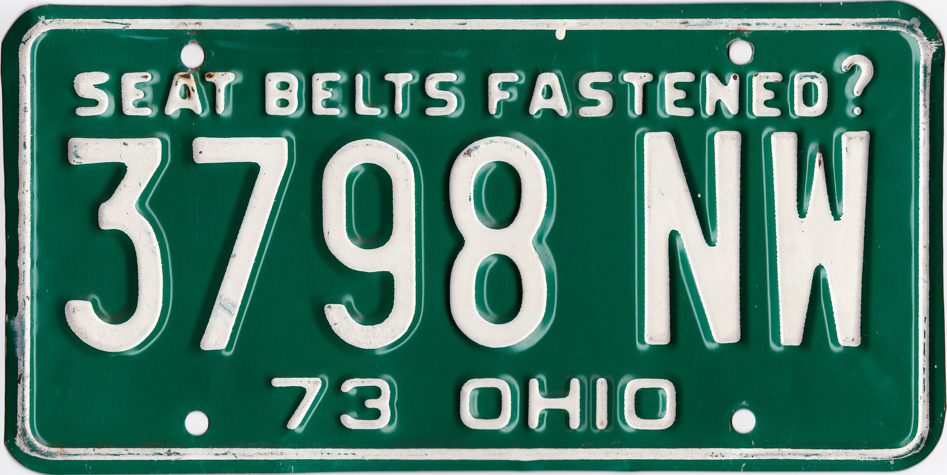 Grüner Ohio-Kennzeichen mit weißem Text "Sicherheitsgurte angelegt?" auf weißem Hintergrund.