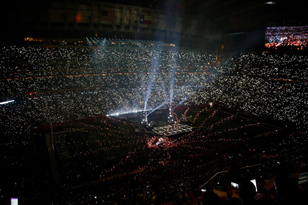 Gro├če Menge in hell erleuchtetem Stadion bei Nacht mit einem Bildschirm auf der rechten Seite, der die Ergebnisse der Super Bowl XLVII-Halbzeit zeigt.
