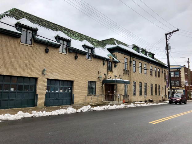 Ein großes Ziegelgebäude mit einem grünen Dach an einer Straßenecke, umgeben von Fahrzeugen, Schnee, Strommasten, Bäumen und einem bewölkten Himmel, identifiziert als die ehemalige St. Louis Fire Station.