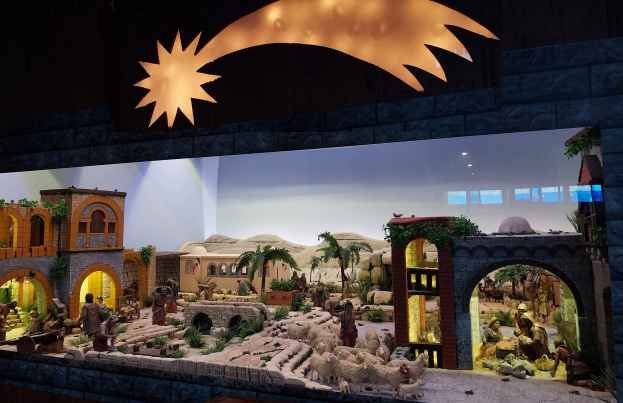 Eine Krippenausstellung im Museum mit Figuren, Tieren und Szenerie, beleuchtet von oben.