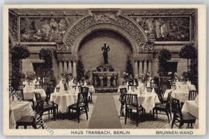 Ein altes Schwarz-Weiß-Foto eines Berliner Restaurants mit Tischen, Stühlen, Blumenvasen und einer Statue im Hintergrund, mit Skulpturen und Pflanzen an den Wänden und Text unten.